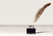 Feather Quill Pen And Glass Inkwell On Desk
