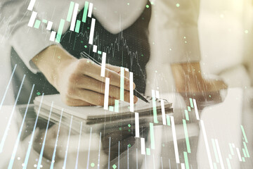 Multi exposure of abstract financial graph with hand writing in notebook on background, financial and trading concept