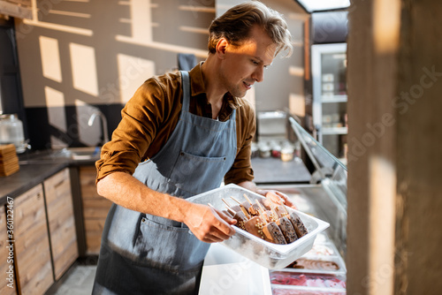 Photographie Portrait of a handsome seller working with ice cream at the counter of pastry sh