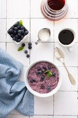 Wall Mural - Blueberry oatmeal for breakfast ith coffee on white table overhead shot