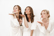 © Drobot Dean - Photo of cheerful beautiful bridesmaids blowing air kiss aside