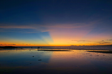 Wall Mural - Kuta beach sunset lans sun rays in blue sky, Bali island, Indonesia