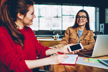 Wall Mural - two happy female friends enjoying positive conversation looking to each other in break of learning a