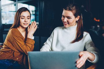 Wall Mural - cheerful hipster girls making video call using web camera on netbook device connected to wifi indoor