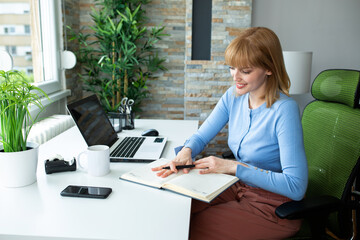 Wall Mural - Young woman taking notes as she works