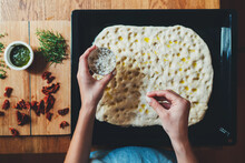 Top View Of Woman Cooking Italian Focaccia Adds Ingredients To The Dough, Italian Focaccia With Rosemary And Sun-dried Tomato, Homemade Food Concept, Cooking Class Online