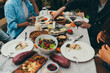 © iana_kolesnikova - Cropped image of best friends dining together by candles at home terrace eating local mediterranean food and drinking homemade wine, Dinner Party Concept, family celebrating having fun together
