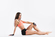 © BestForYou - Beautiful fitness woman slim figure in sportswear posing in the studio. Sporty girl sitting on the floor in full.
