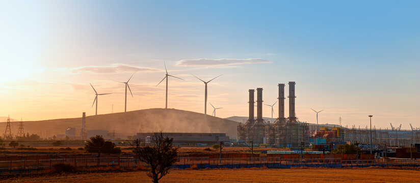 industrial concept - silhouette of natural gas processing plant with renewable energy wind turbines 