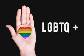 LGBTQ communities. Hand of a man with a rainbow flag on a black background.