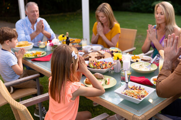 Caucasian family saying grace together before eating