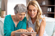 © wavebreak3 - Senior Caucasian woman and her adult daughter using a tablet at home