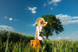 Blonde woman with suitcase and camera in wheat field in summer time
