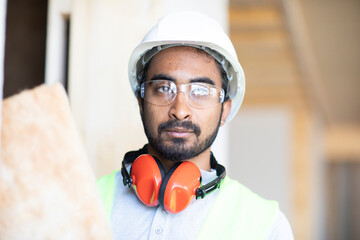 Junger Handwerker, Mann mit Helm, erstellt ein Holzgebäude