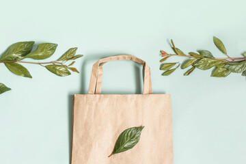 Wall Mural - Recycled brown paper shopping bag with handle and green branches leaves isolated on white background. Zero waste concept. Top view, flat lay.