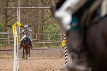 A knight in vintage armor of the 15th century rides a horse across a field for a tournament