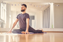 Athletic Young Man Doing Pigeon Pose In Yoga Studio