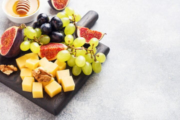 Wall Mural - Cheese cubes, fresh fruit figs grapes Honey walnut on wooden chopping Board. Copy space.