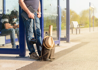 Men waiting for train with green travel backpack, hat, maps, glasses on the platform at the  train station at the sunset