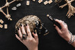 Cropped view of woman holding candle near skull, runes and crystals on black