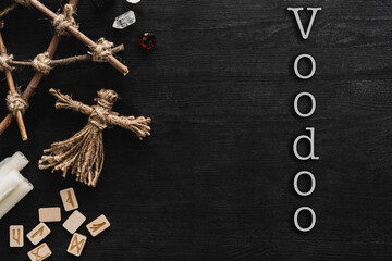 Poster - top view of voodoo dolls, ancient runes, pentagram, candles and crystals near voodoo lettering on black