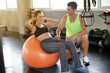 © Pruksachat - A Caucasian young fit woman working out with fitness ball and her muscular trainer at the gym