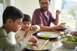 © trevor adeline/Caia Image - Family eating lunch at table