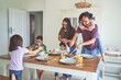 © trevor adeline/Caia Image - Family eating lunch at dining table