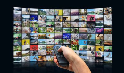 Streaming video services. Man using remote control to change channels on TV