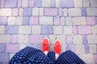 Female feet seen from above. Selfie for any use. Foot and legs in red sneakers. Foot standing on the colorful paving stones. With copy space. Feet outside