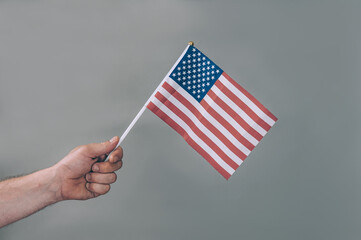 The guy holds in his hand the national flag of the United States of America.