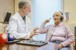 © fStop - Senior patient wearing headphones talking to Audiologist during ear exam at doctor's office