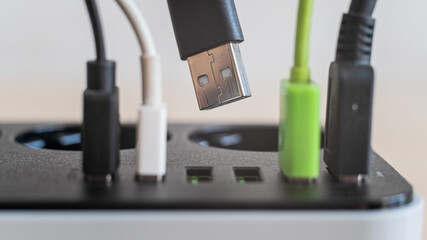 Modern convenient multi-port usb charger for devices. Close-up of inserted multi-colored cables in a power outlet. Macro.