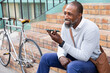 © wavebreak3 - African American man sitting on stairs and having a phone call