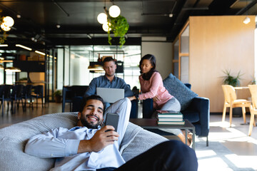 Caucasian man using his phone on a bean bag in a co working zone