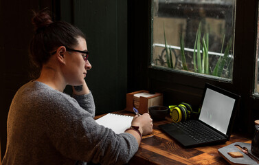A young student works on a table near a pub window. Close up view