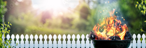 Fotomural Barbecue Grill With Wood Fire In Backyard With Picket fence And Sunset Backgroun