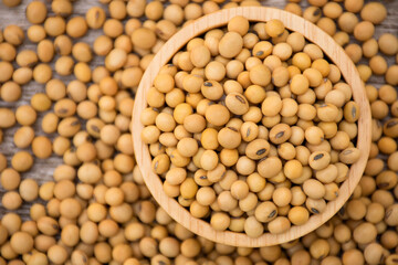 Wall Mural - Closeup soy beans in wooden bowl isolated on wood table background. Overhead view. Flat lay.