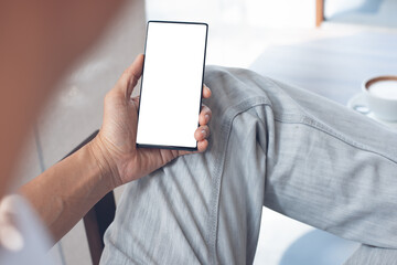 Poster - Mockup of man hand holding and looking at mobile phone in coffee shop