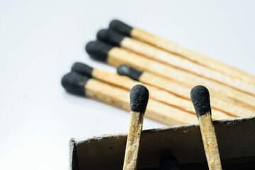 two match sticks in focus over the edge of a match box and multiple match sticks laying on the floor