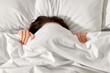people, bedtime and rest concept - woman lying in bed under white blanket or duvet