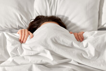 people, bedtime and rest concept - woman lying in bed under white blanket or duvet