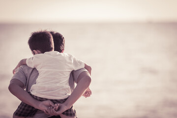 The happiness of Asian young father and son on the evening beach during the summer holidays