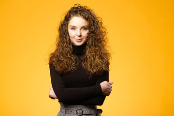 Wall Mural - Pretty girl with curly hair on yellow background