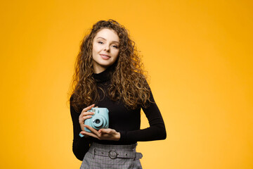 Wall Mural - Beautiful girl with photo camera isolated on yellow background