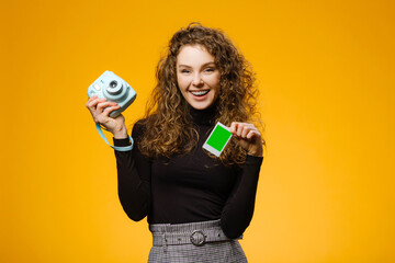 Wall Mural - Beautiful girl with photo camera isolated on yellow background