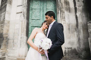 Lovely happy wedding couple, bride with long white dress posing in beautiful city