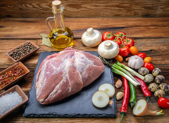 Wall Mural - pork tenderloin in one piece on a slate stone with fresh vegetables and spices in the village style