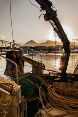 Poster - Sunset on the water and mountains seen from a boat full of ropes and tools