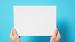 © nisara - The hand is holding the white A4 paper on blue background.